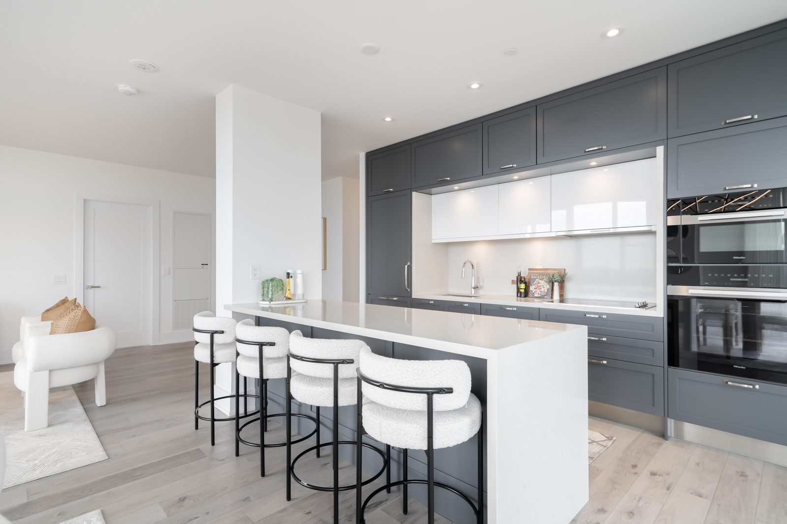 Kitchen with a waterfall island, bouclé stools and built-in ovens