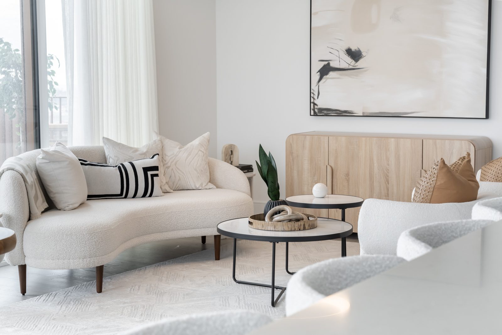 Living room with a curved sofa, nesting tables and abstract art